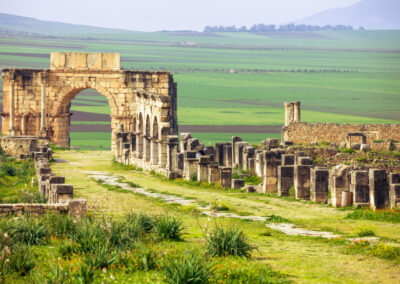 Ancient Roman ruins of Volubilis with stone columns and mosaic floors under clear skies Atlas itinerary,